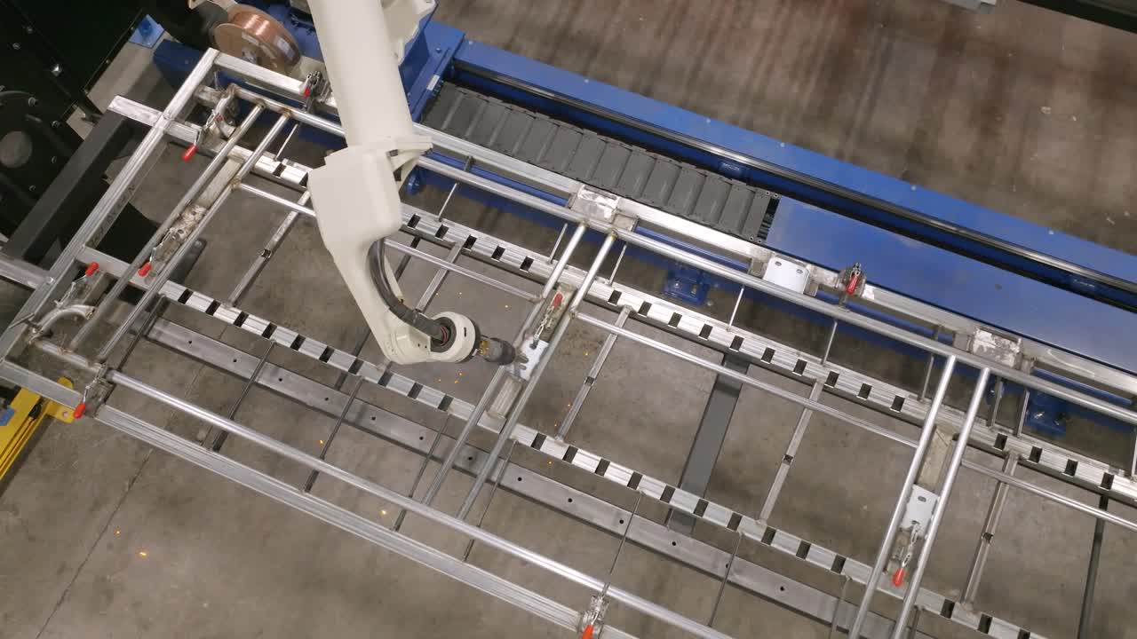Aerial footage of a robotic welding machine at a factory working on a steel frame