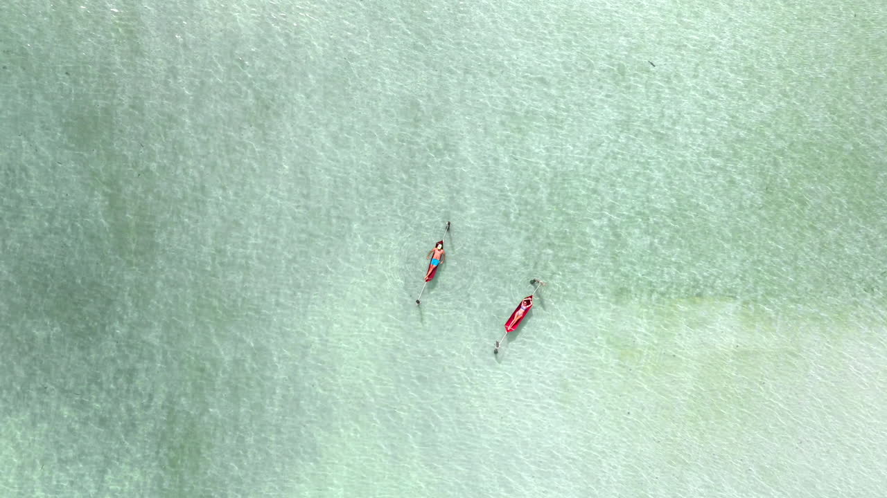 Aerial ascend of two tourists relaxing in water hammocks, Koh Rong Samloem, Cambodia