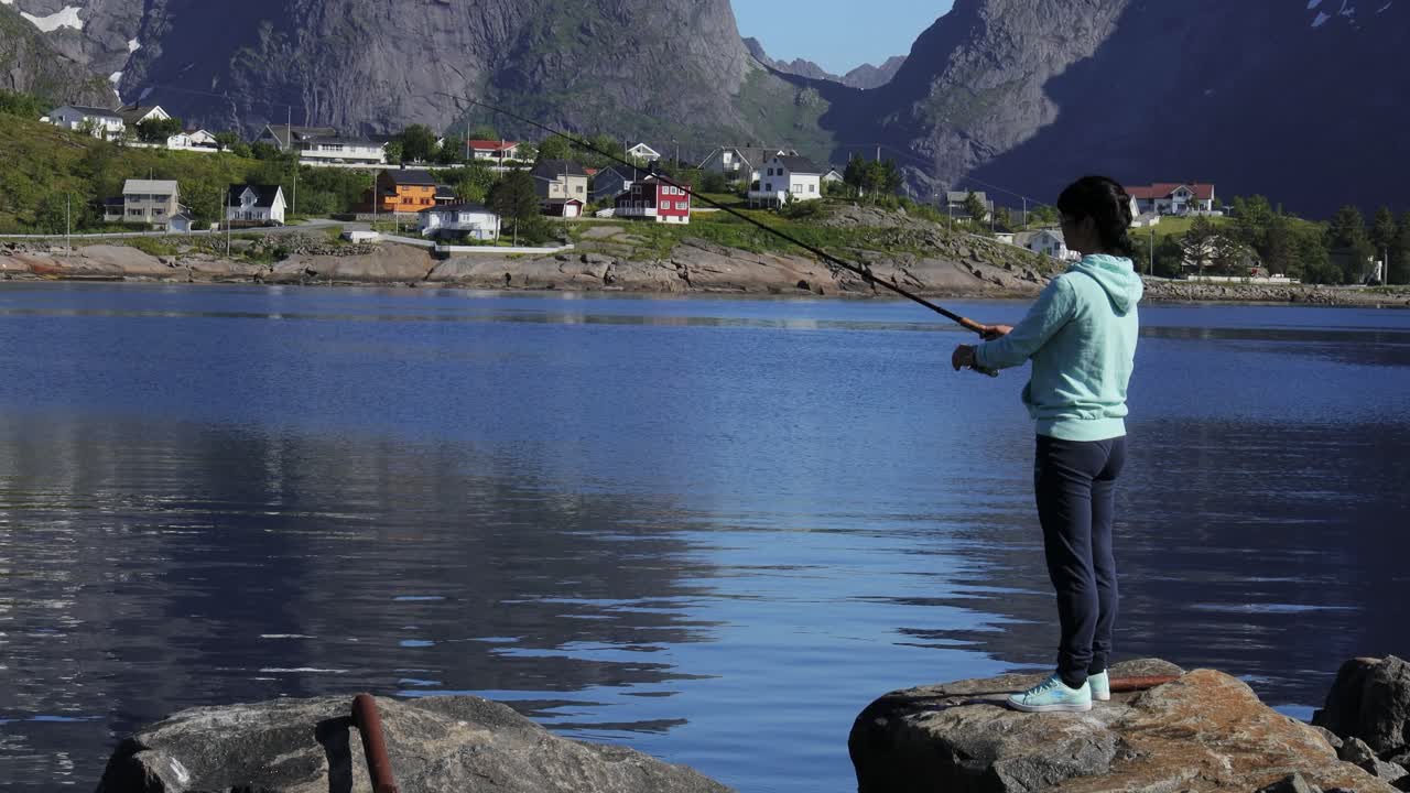 mujer pescando en una caña de pescar girando en noruega.