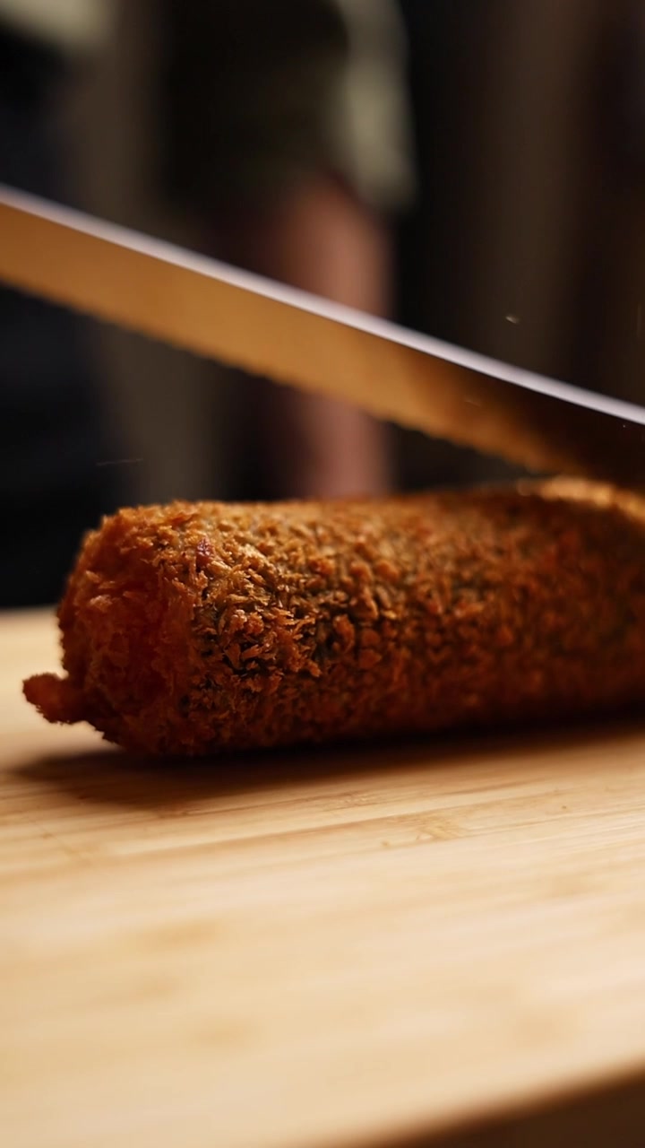 Cutting a Crispy Fried Croquette on a Wooden Board