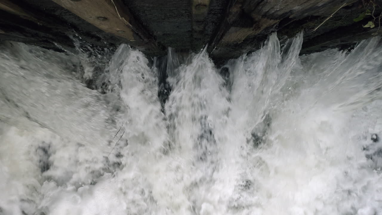 The raging waters of the river Alne in Warwickshire, England as it passes through sluice gates that control the amount of flood water after torrential rainfall
