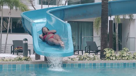 lady in red swimsuit slides down blue plastic water slide