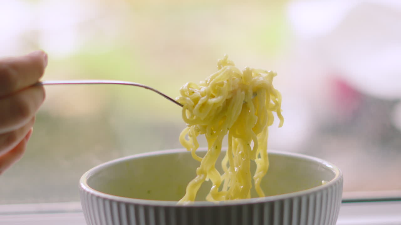 Freshly Cooked Noodles Being Picked Up with a Fork by Female Hand for Tasty Lunch Snack