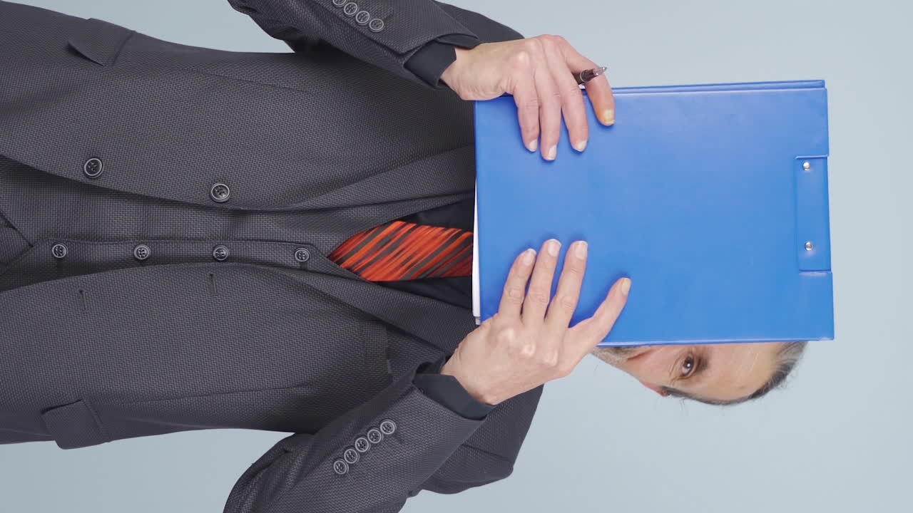 Vertical video of Old businessman looking from behind files.