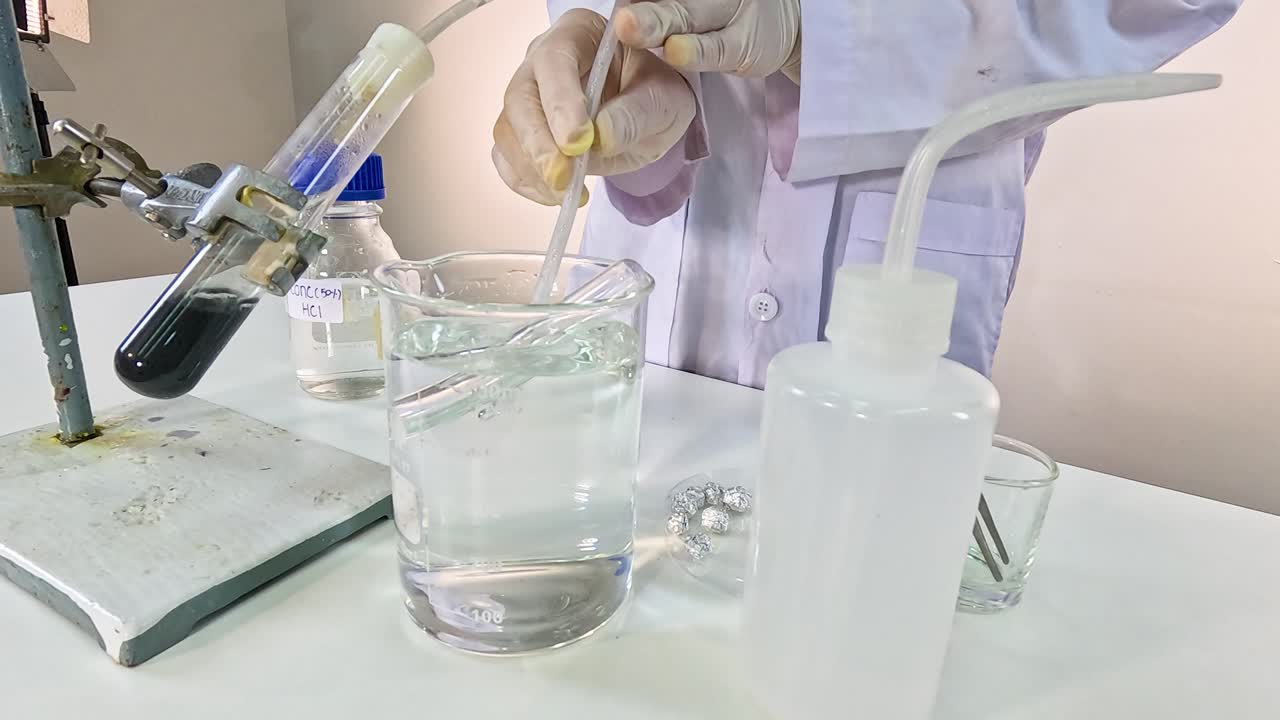 A scientist conducts a thermal decomposition experiment with copper carbonate, using a test tube and beaker setup in a lab