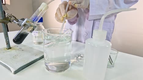 a scientist conducts a thermal decomposition experiment with copper carbonate, using a test tube and beaker setup in a lab