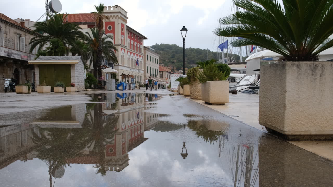 크로아티아 비스 섬의 비스 항구에 있는 해안가 건물이 있는 산책로 바닥에 물 웅덩이