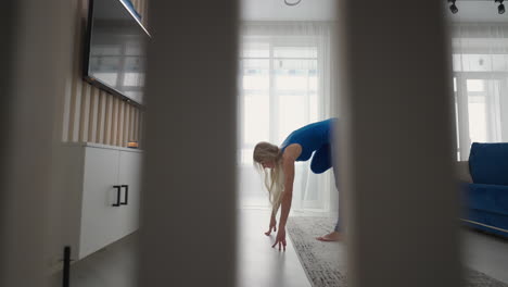 staying at home in quarantine and working remotely from home a woman trains and does balance exercises while standing on the carpet. sportswear doing workout burning fat calories training strength