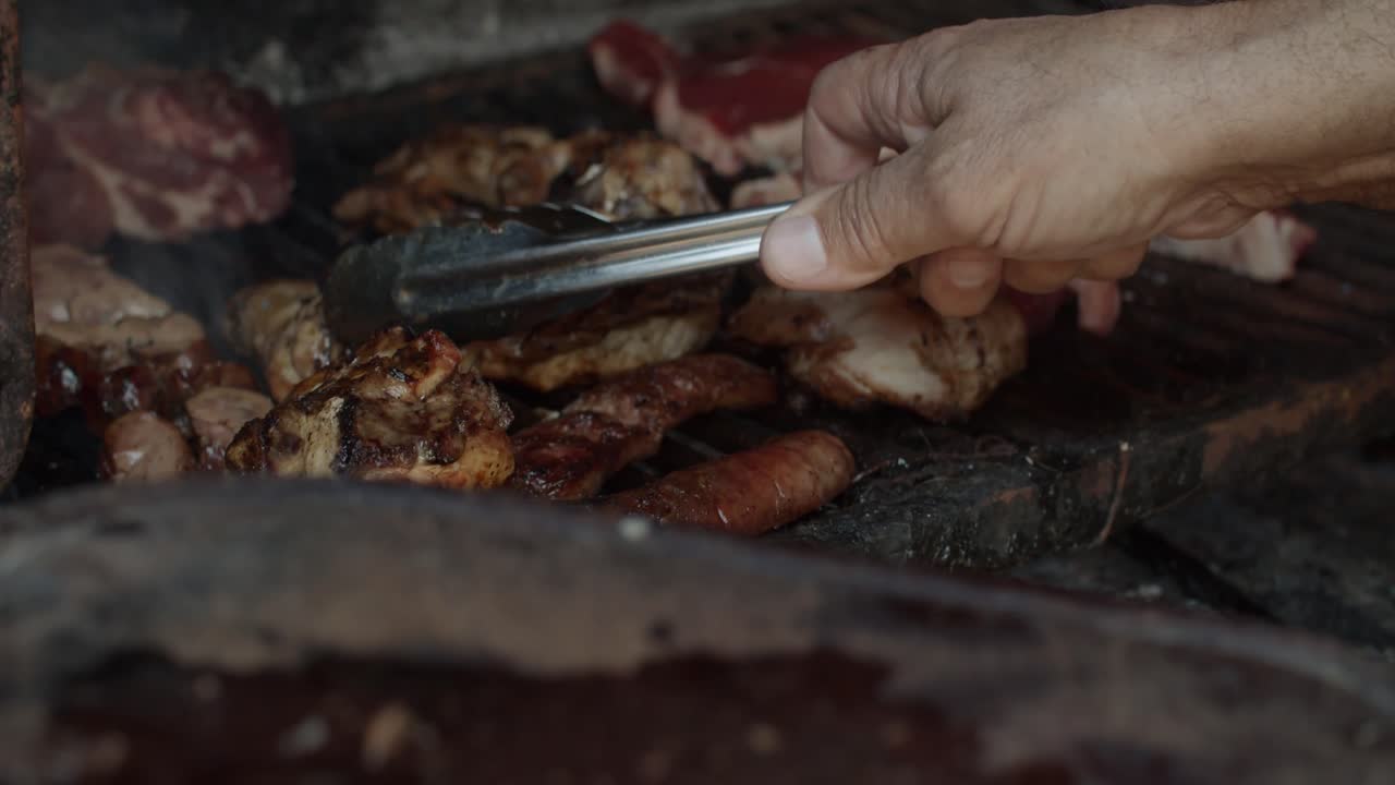4K at 60fps (slow motion) - Man cooking a barbecue on a rusty grill on a sunny day - BBQ (asado) - Relax and warm mood