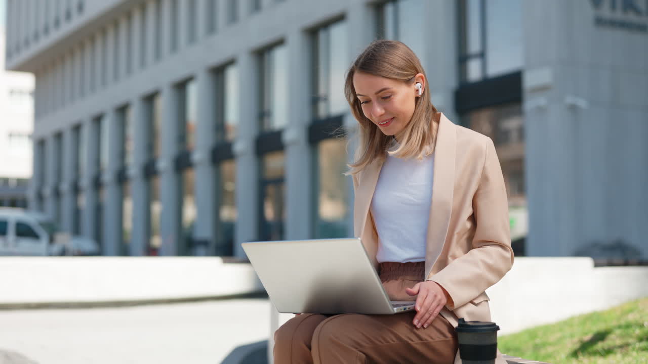 Giovane donna in videochiamata con il laptop all'aperto in città.