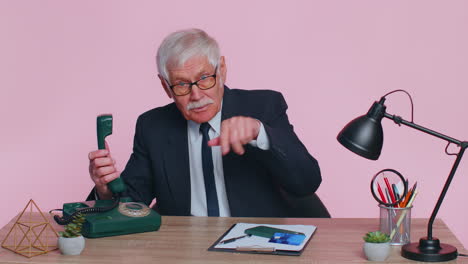 Senior-businessman-talking-on-wired-vintage-telephone-of-80s,-says-hey-you-call-me-back-at-office