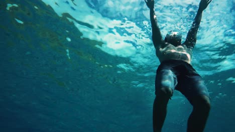 Man-dolphin-kicks-to-the-surface-from-deep-water