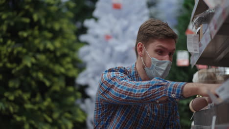 shopping in pandemic and quarantine. a man in a protective mask in a jewelry store and garlands with toys for christmas trees and at home. christmas garlands and decor.