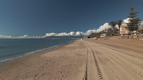 avanzando en una playa vacía con un cielo azul brillante