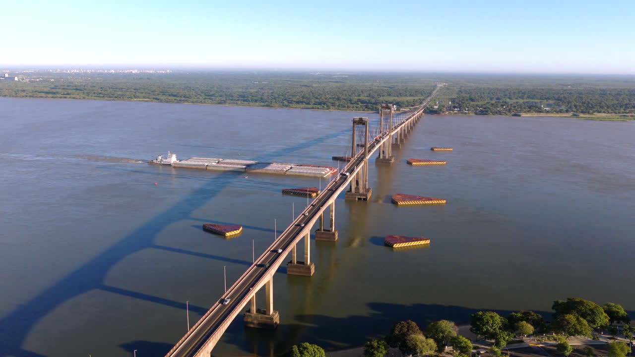 Drone perspective of the Paraná River showing barge traffic beneath the General Belgrano Bridge connecting Corrientes to neighboring regions