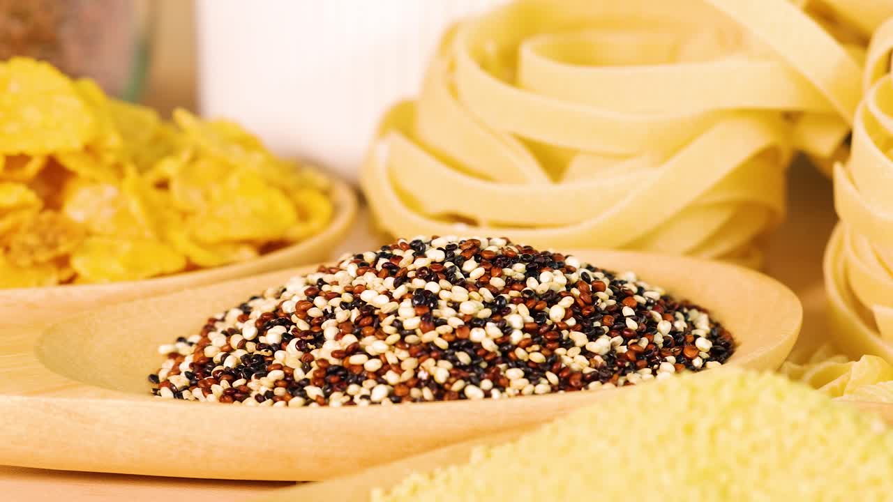A variety of grains and pasta arranged in a warm, inviting setting. Includes quinoa, tagliatelle, and whole wheat bread