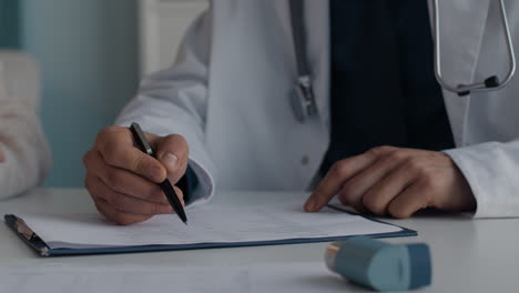 a doctor filling out medical records with an asthma inhaler on the table
