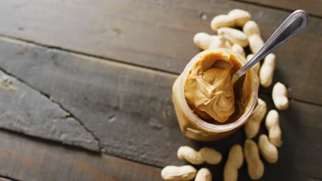 Video-of-close-up-of-peanut-butter-and-peanuts-on-wooden-background