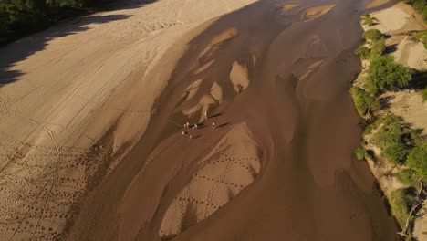 Family-walking-on-dry-river-bed,-Cordoba-in-Argentina