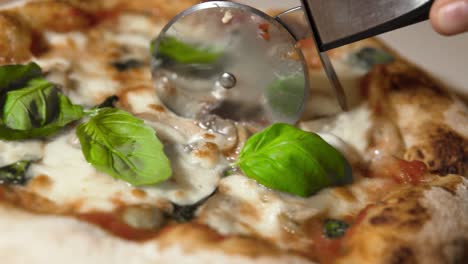 affettare una calda e deliziosa pizza napoletana fatta in casa con basilico e olive