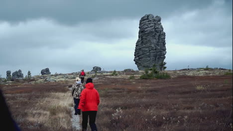 hikers on a mountain path with a large rock formation