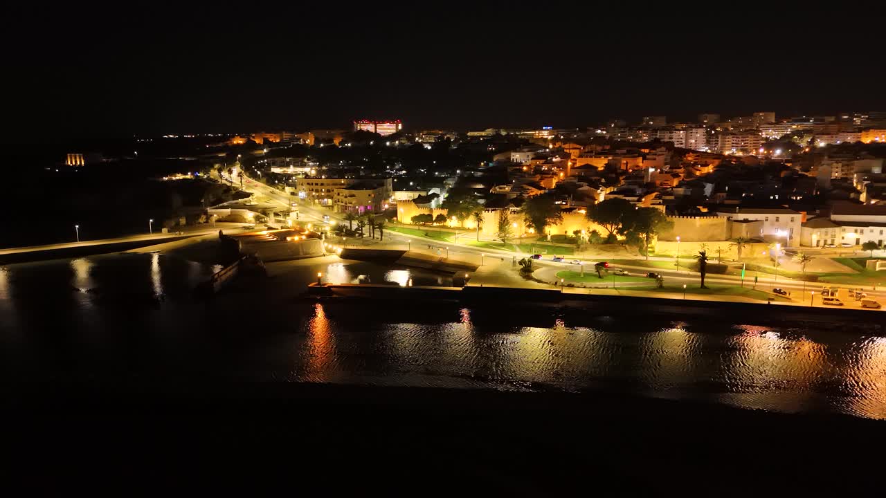 Aerial view of Lagos, Portugal illuminated at night showing the Bensafrim river and the city lights
