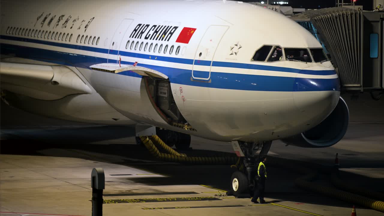 Under the night sky, an Air China aircraft is parked on a runway at Beijing International Airport, China.