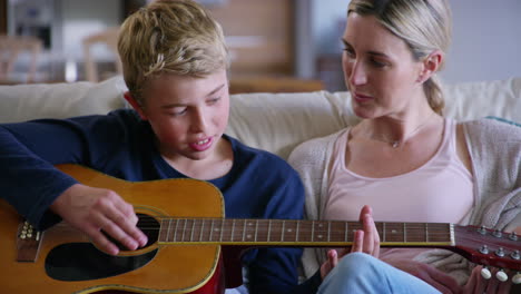 mother teaching her son to play the guitar