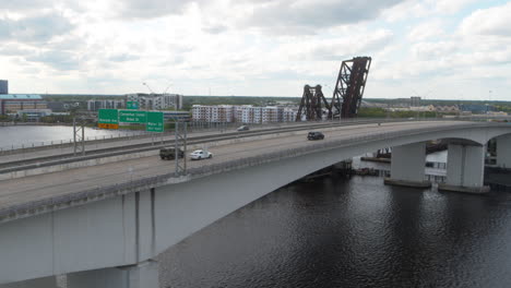 Imágenes-Aéreas-Que-Siguen-A-Un-Automóvil-Que-Cruza-Un-Puente-De-Carretera-Durante-El-Día-En-Jacksonville,-Florida