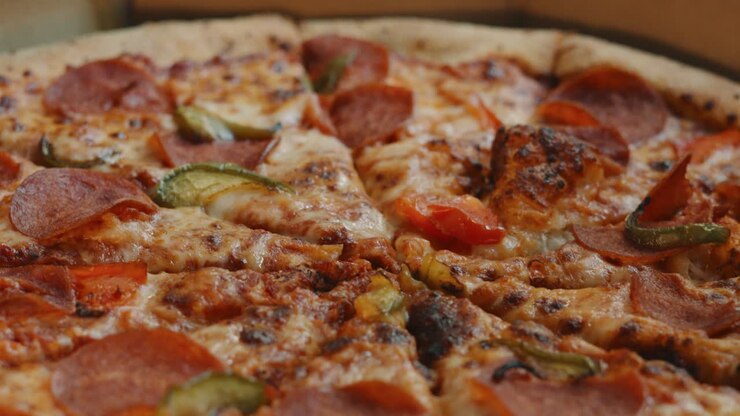 Ripresa in allontanamento di una pizza da asporto con pepperoni e peperoni verdi