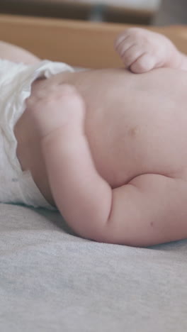 adorable fair haired newborn son lies on baby changing table and cries and nurse turns infant close view