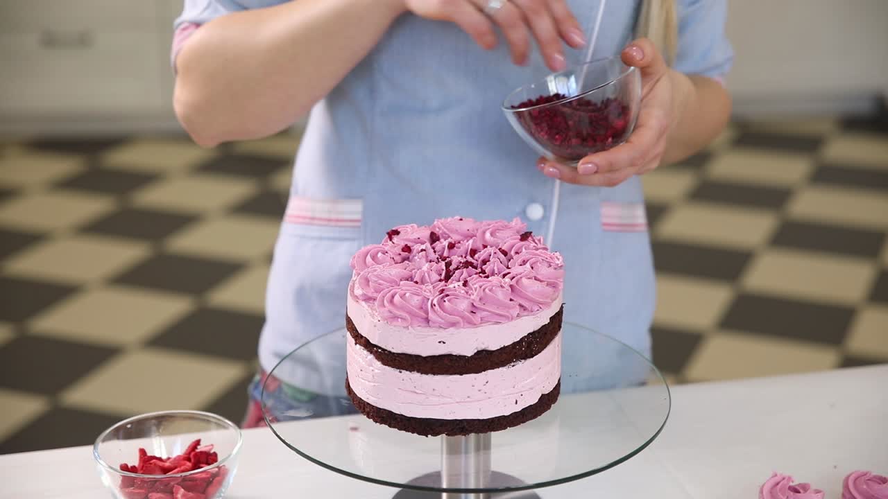 분홍색 라즈베리 케이크를 장식하는 여자