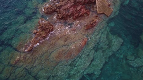 Aerial-bird's-view-of-incredible-lighthouse-reveals,-offshore-rocks,-zoom-out