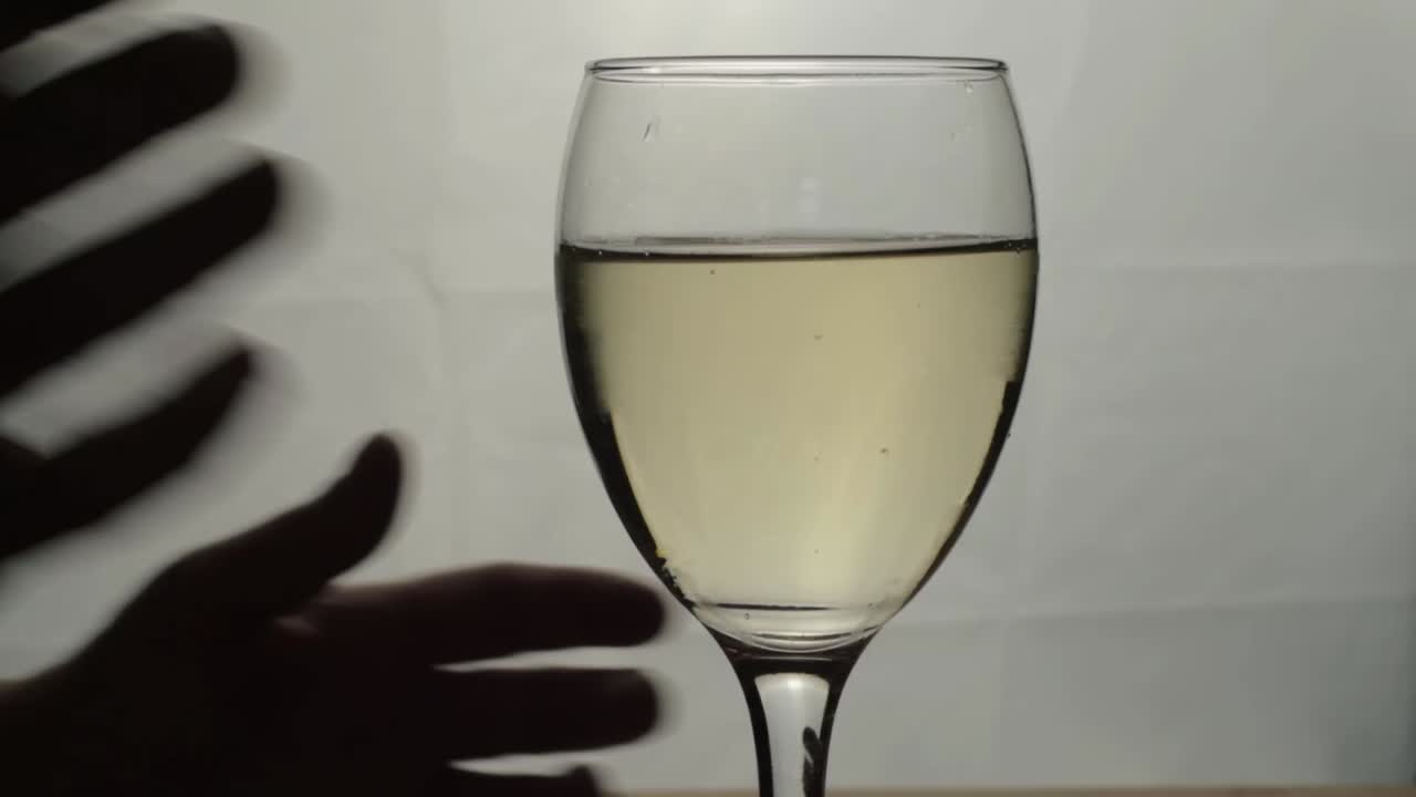 Two hands holding glass of white wine silhouette close up shot