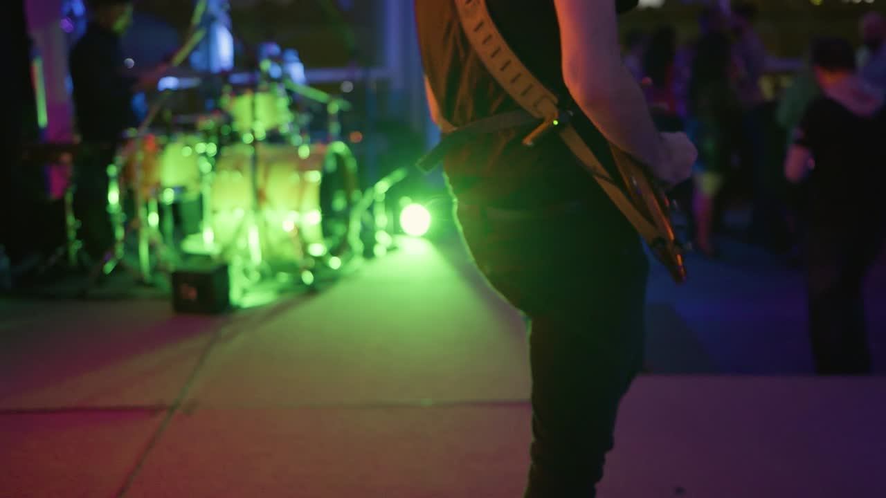 Początkujący gitarzysta rockowy podciągający struny na progach Stratocastera podczas występu.