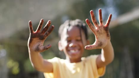 portrait of happy african american boy showing hands covered with soil, slow motion