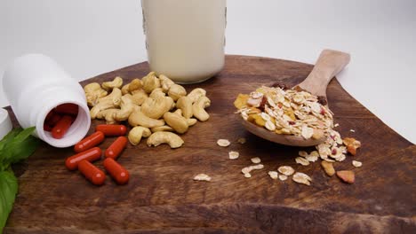 una bandeja de madera con suplementos, nueces de anacardo, cuchara de cereal y leche de avena vegana en el fondo