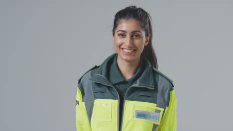 Studio-Portrait-Of-Smiling-Young-Female-Paramedic-Against-Plain-Background