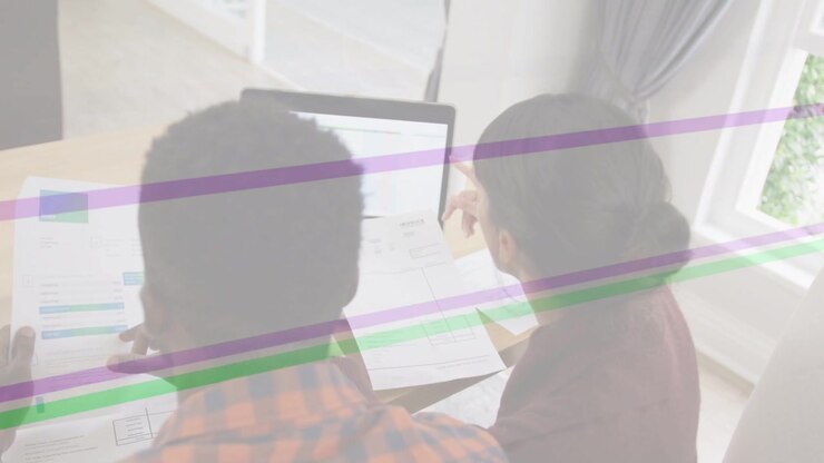 Man and woman sitting at desk, woman tapping laptop, man aligning papers, reviewing for business