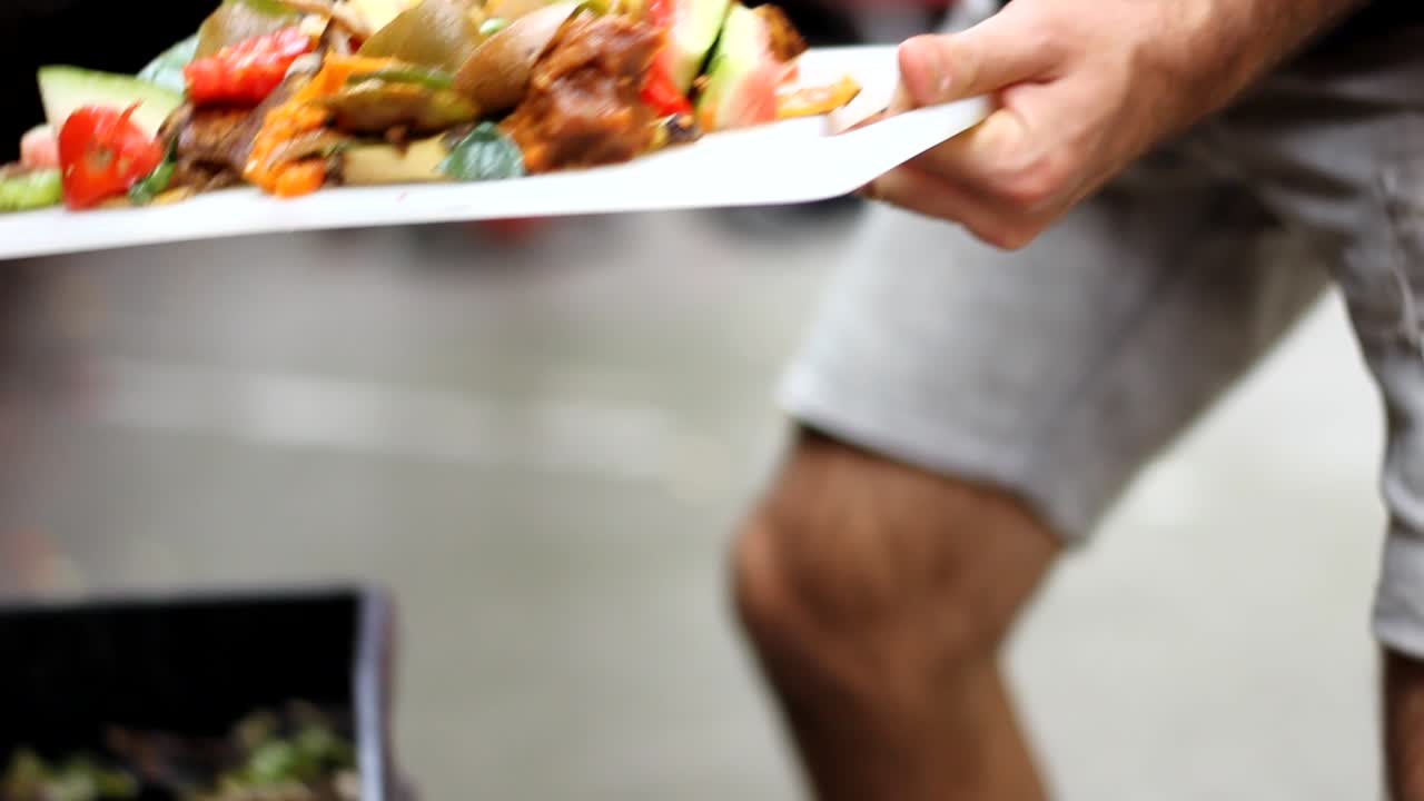Tracking shot of man putting Food Waste Into Backyard Compost Bin. Food scraps for compost.