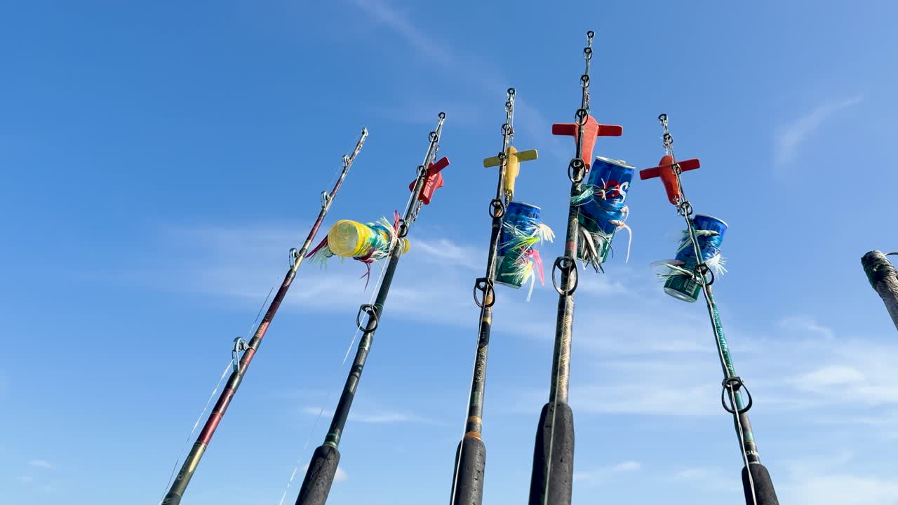 Fishing rods with colorful flags sway gently under a clear blue sky in Phuket, Thailand