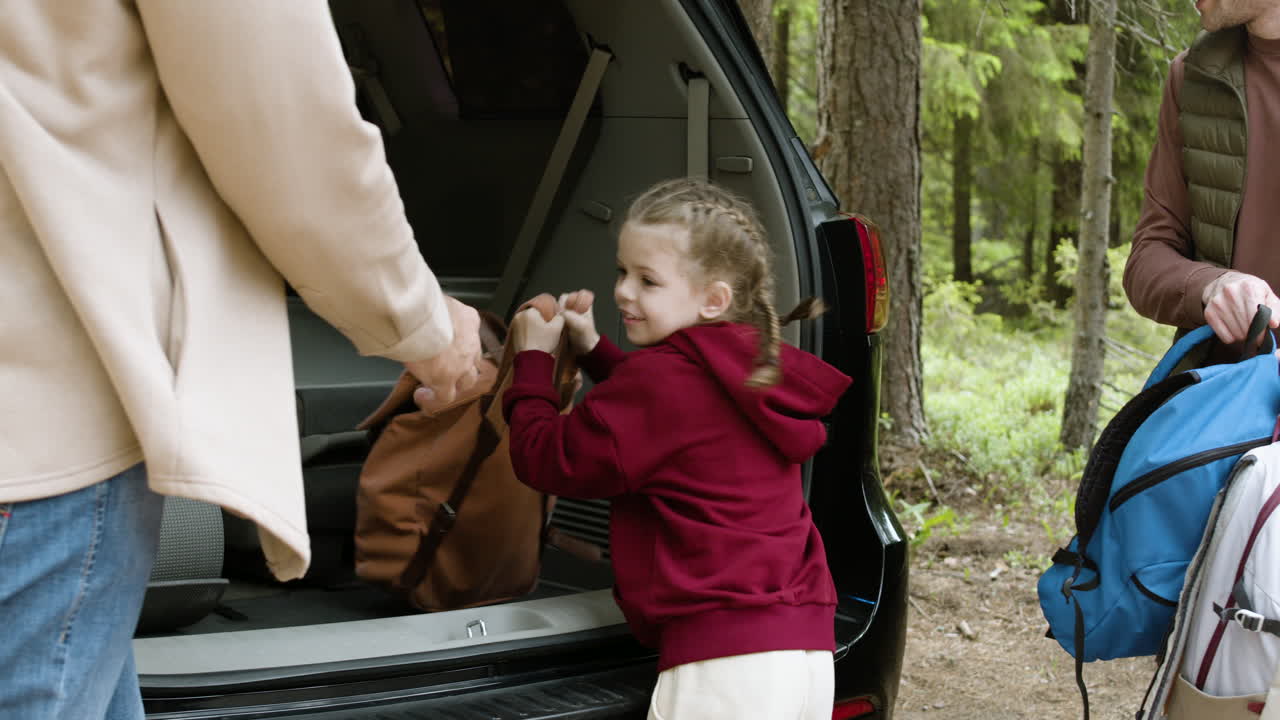 Blonde girl giving backpacks to her parents