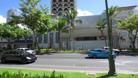 Verkehr,-Der-Die-Kalakaua-Avenue-In-Waikiki,-Honolulu,-Hawaii-Mit-Palmen-Hinunterfährt