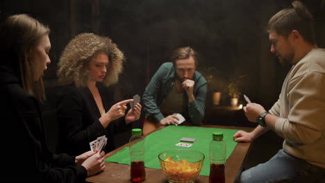 gruppe von freunden, die poker spielen und zu hause auf stühlen an einem tisch sitzen 3