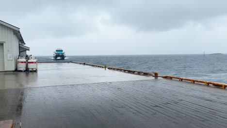 Passenger-high-speed-catamaran-boat-is-approaching-a-pier-in-Norway-on-a-rainy-day,-panning-shot