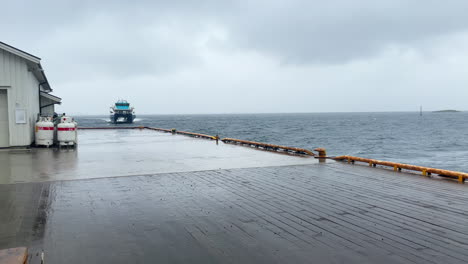 passenger high speed catamaran boat is approaching a pier in norway on a rainy day, panning shot