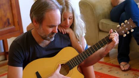 Vater-Spielt-Gitarre-Mit-Ihrer-Tochter-Im-Wohnzimmer-4K