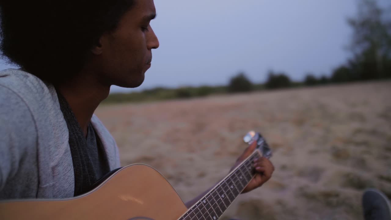 Håndholdt video af afrikansk mand der spiller guitar på stranden/Dabrowa Gornicza/Polen
