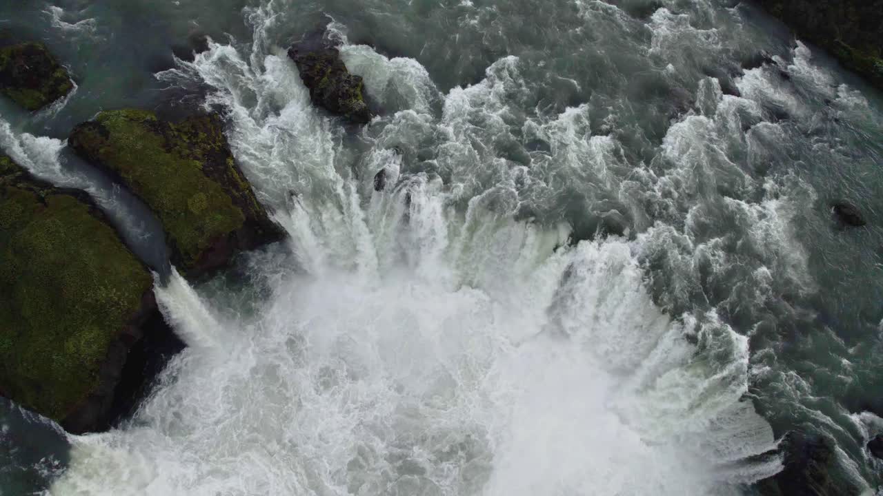 Drone flying backwards with the camera tilting up filming a large cirulair formed waterfall in Iceland in 4k