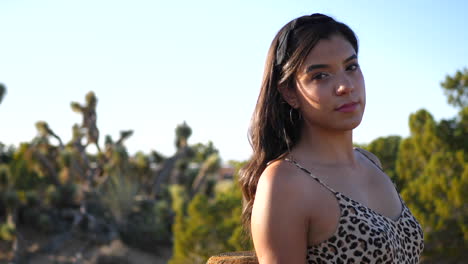 a beautiful hispanic woman modeling and posing with serious staring eyes outdoors in a desert nature landscape